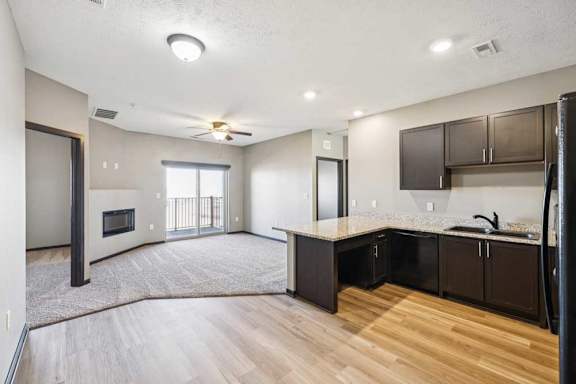 A modern kitchen with dark brown cabinets and a wooden floor.