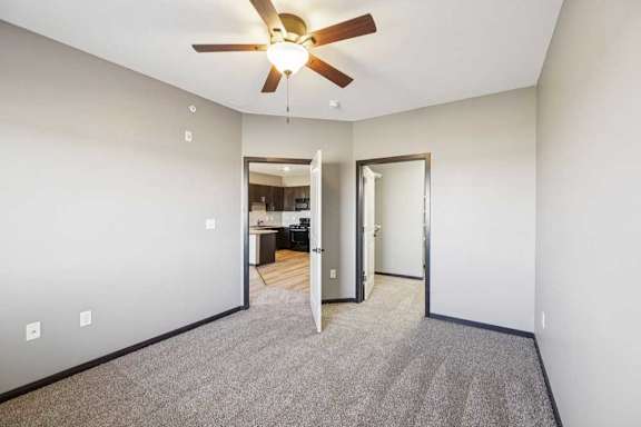Bedroom with carpet and ceiling light, featuring an open closet and direct access to a bathroom with wood-style flooring.