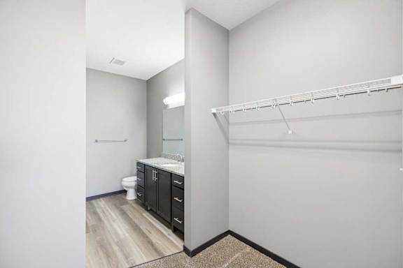 A white bathroom with a toilet, sink, and a shelf.