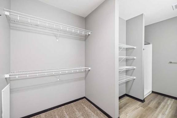 A white walk-in closet with shelves and an open door.