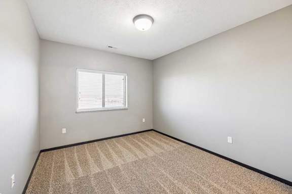 A room with a carpeted floor and a window with blinds.