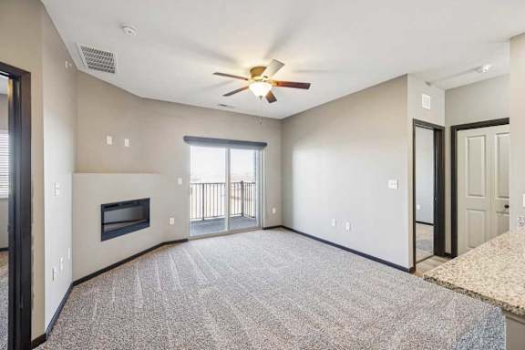 A spacious living room with a fireplace and a ceiling fan.