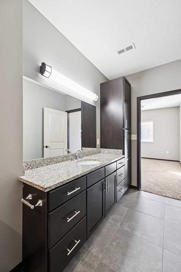 A bathroom with a sink, mirror, and cabinets.