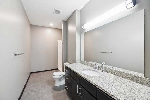 A bathroom with a toilet, sink, and mirror.