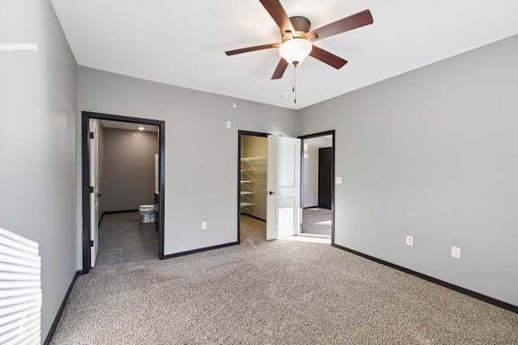 A room with a ceiling fan and carpeted floor.