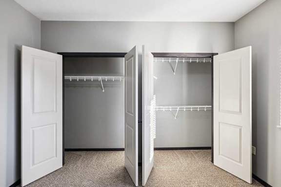 A white closet with two doors open and shelves.