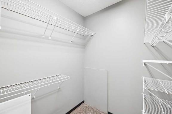 Empty white walk-in closet with shelves and hangers.