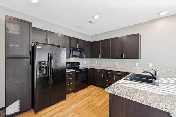 A kitchen with a black refrigerator, microwave, and oven.