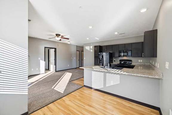 A modern kitchen with a wooden floor and a ceiling fan.