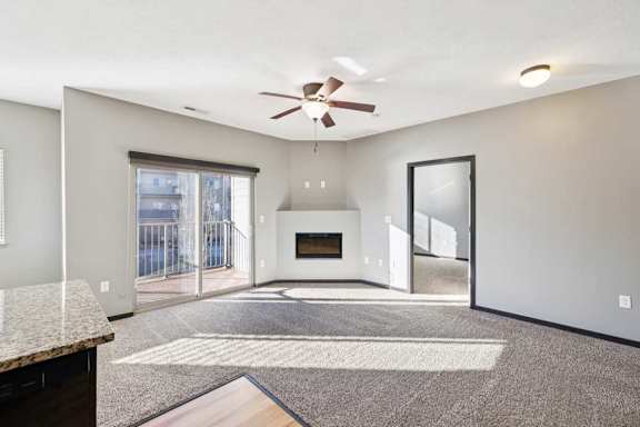 A spacious living room with a fireplace and a ceiling fan.
