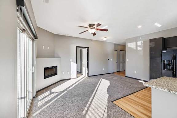 A modern living room with a fireplace and a ceiling fan.