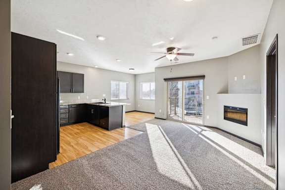 A modern kitchen with a dark wood floor and a ceiling fan.