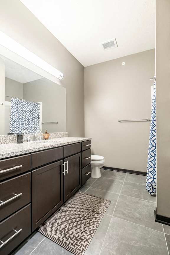 Bathroom with granite countertops and tile flooring at The Flats at 84 in southeast Lincoln NE 68516