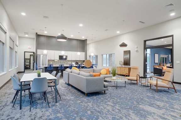 Resident clubhouse with fireplace, lounge seating, and modern finishes in an open-concept community gathering space.