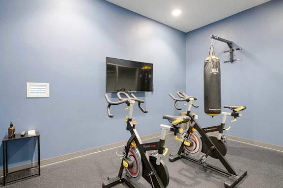 Yoga studio with punching bag, stationary bikes, and mounted TV