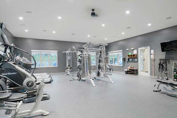 Spacious fitness center with cable machines, strength equipment, and expansive open floor space for exercise.