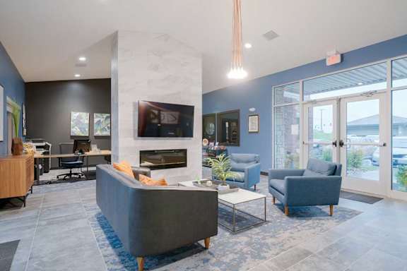 Resident clubhouse lounge with fireplace, comfortable seating, high ceilings, and large windows bringing in natural light.