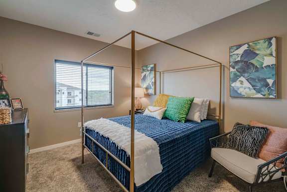a bedroom with a bed and a chair and a window