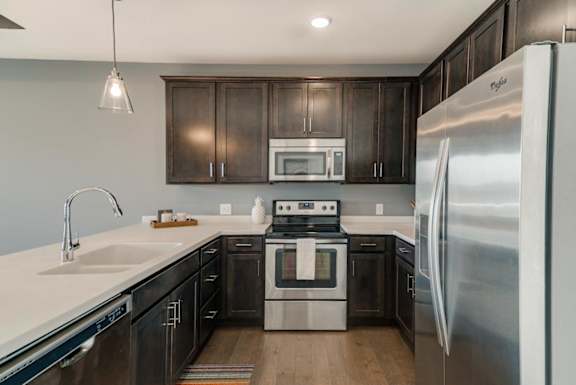 A modern kitchen with dark wood cabinets and stainless steel appliances.