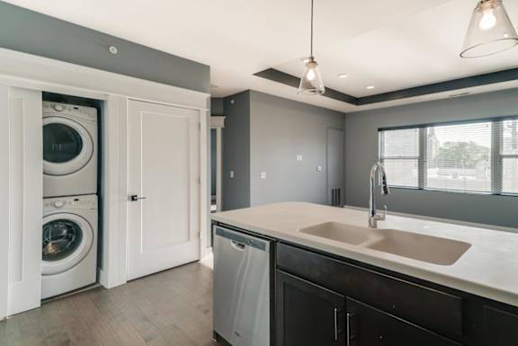 A modern laundry room with a washer and dryer in the cabinet.