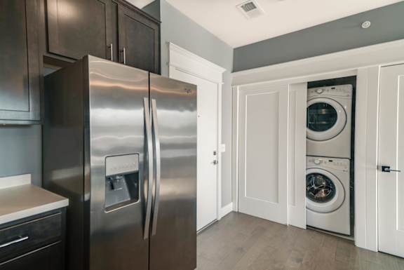 A modern kitchen with a stainless steel refrigerator and white cabinets.