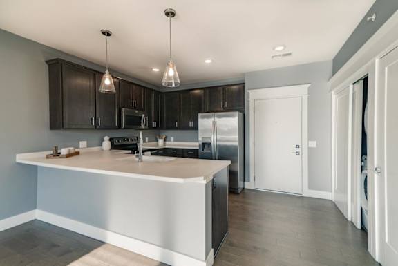 A modern kitchen with dark wood cabinets and stainless steel appliances.