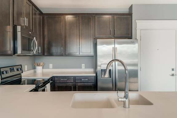 A modern kitchen with dark brown cabinets and stainless steel appliances.