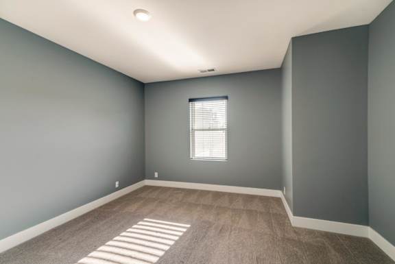 A room with a window and a carpeted floor.