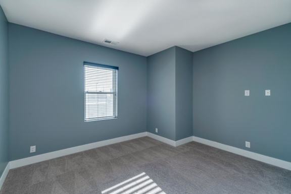 A room with a window and a carpeted floor.