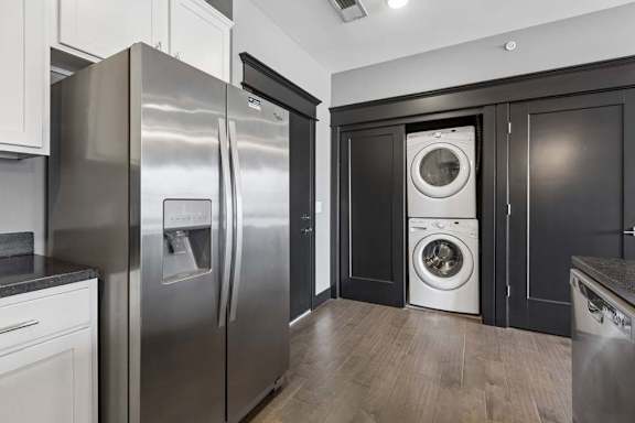 In-home laundry is tucked beside the apartment kitchen, with a stacked washer and dryer framed by dark doors and trim.