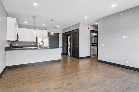Open living space connects to a white-cabinet kitchen and tucked-away laundry area, finished with wood-look floors and dark trim.