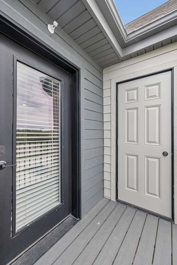 Apartment balcony with private storage closet, gray siding, and wood-look decking.
