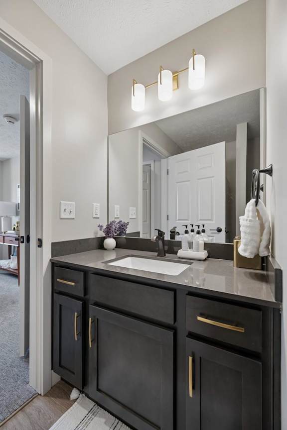 Apartment bathroom vanity with dark cabinetry, framed mirror, and modern lighting.