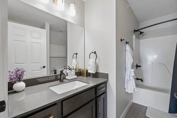 Apartment bathroom with double vanity, dark cabinetry, and blue shower curtain.