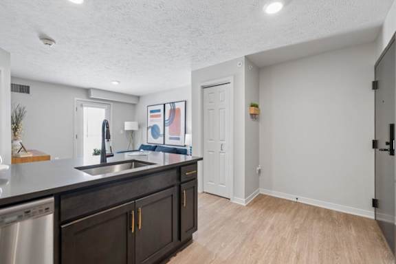 Open apartment kitchen with island and wood-style flooring.
