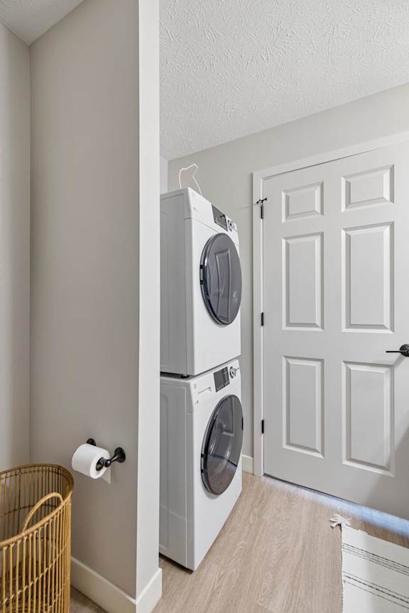 Apartment laundry area with stacked washer and dryer beside paneled doors.