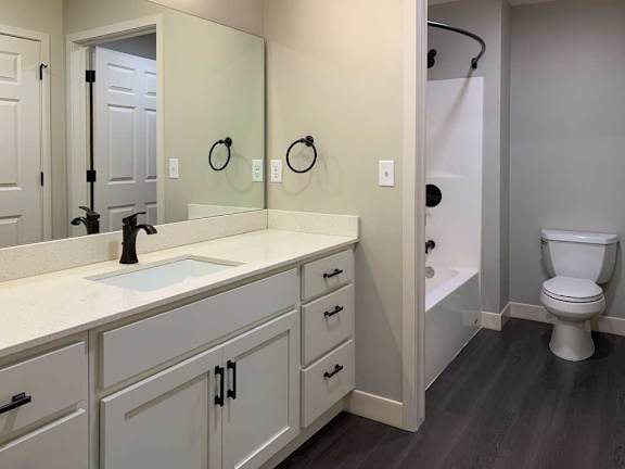 bathroom with a white sink, tub, shower, and toilet.