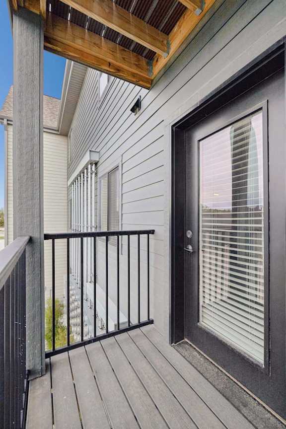 Apartment balcony with privacy railing, gray siding, and glass patio door.