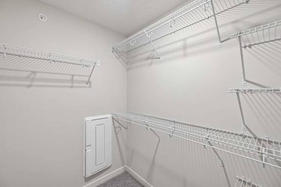 Walk-in closet with built-in wire shelving, hanging space, and attic access panel.
