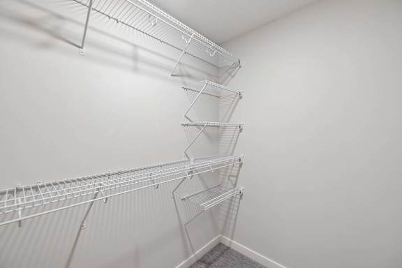 Walk-in closet with built-in wire shelving, multiple hanging racks, and neutral finishes.