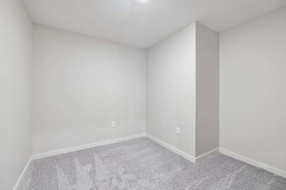 Apartment bedroom with neutral carpeting, recessed wall nook, and light gray walls.