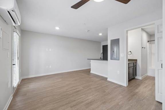 Spacious apartment living room with wood-style flooring, recessed lighting, a ceiling fan, and an open layout connecting to the kitchen and bathroom.