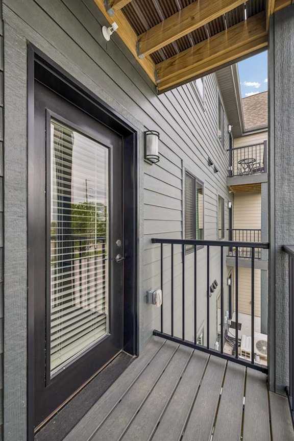 Apartment balcony with glass patio door, privacy railing, and covered outdoor space.