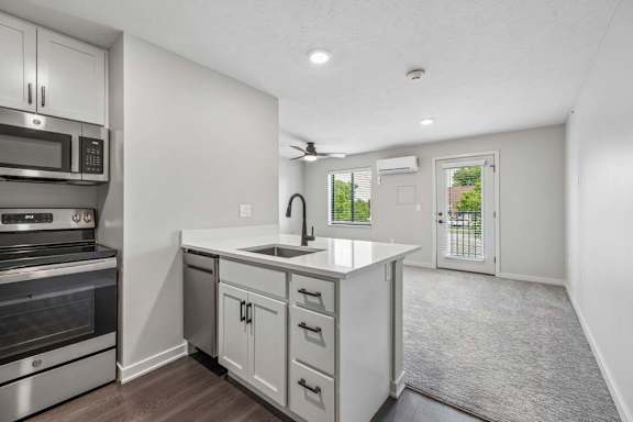 Open apartment living area with kitchen island, stainless steel appliances, and private balcony access.
