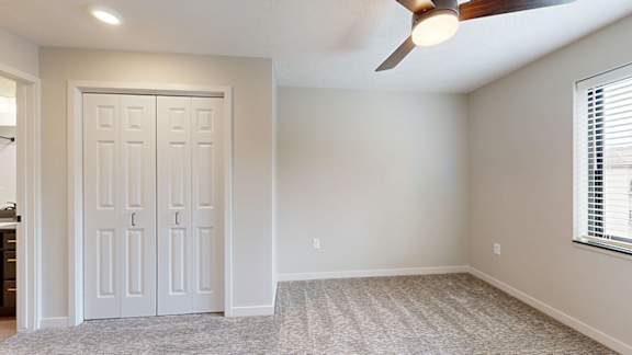 A room with bifold closet doors and a ceiling fan.