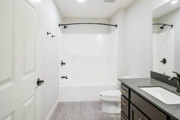 The primary attached bathroom featuring a tub shower with modern dark finishes