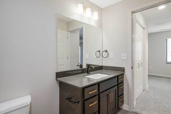 The primary attached bathroom featuring a vanity sink with dark cabinets