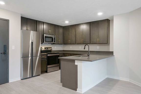 A U-shaped kitchen with dark cabinets and stainless steel appliances