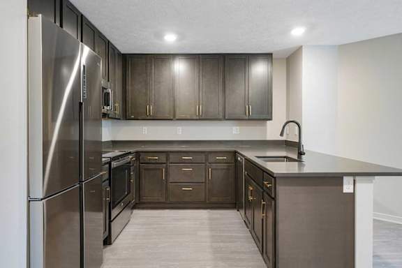 A U-shaped kitchen featuring dark cabinets and stainless steel appliances