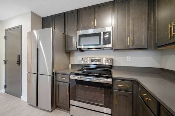 A U-shape kitchen featuring dark cabinets and stainless steel appliances